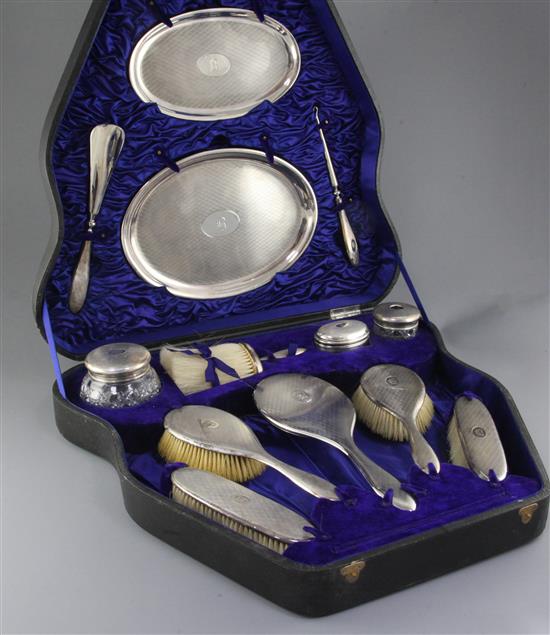 A cased George V thirteen piece engine turned silver dressing table set by Charles & Richard Comyns, largest tray 11.25in.